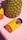 A large pineapple stands next to a bottle of gummy supplements labeled 'Better Day' on a pink background. The bottle has a bright yellow label and is tilted on its side.