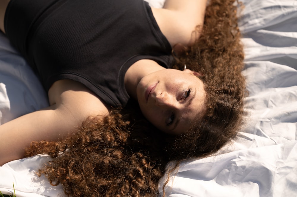 a woman laying on top of a white bed