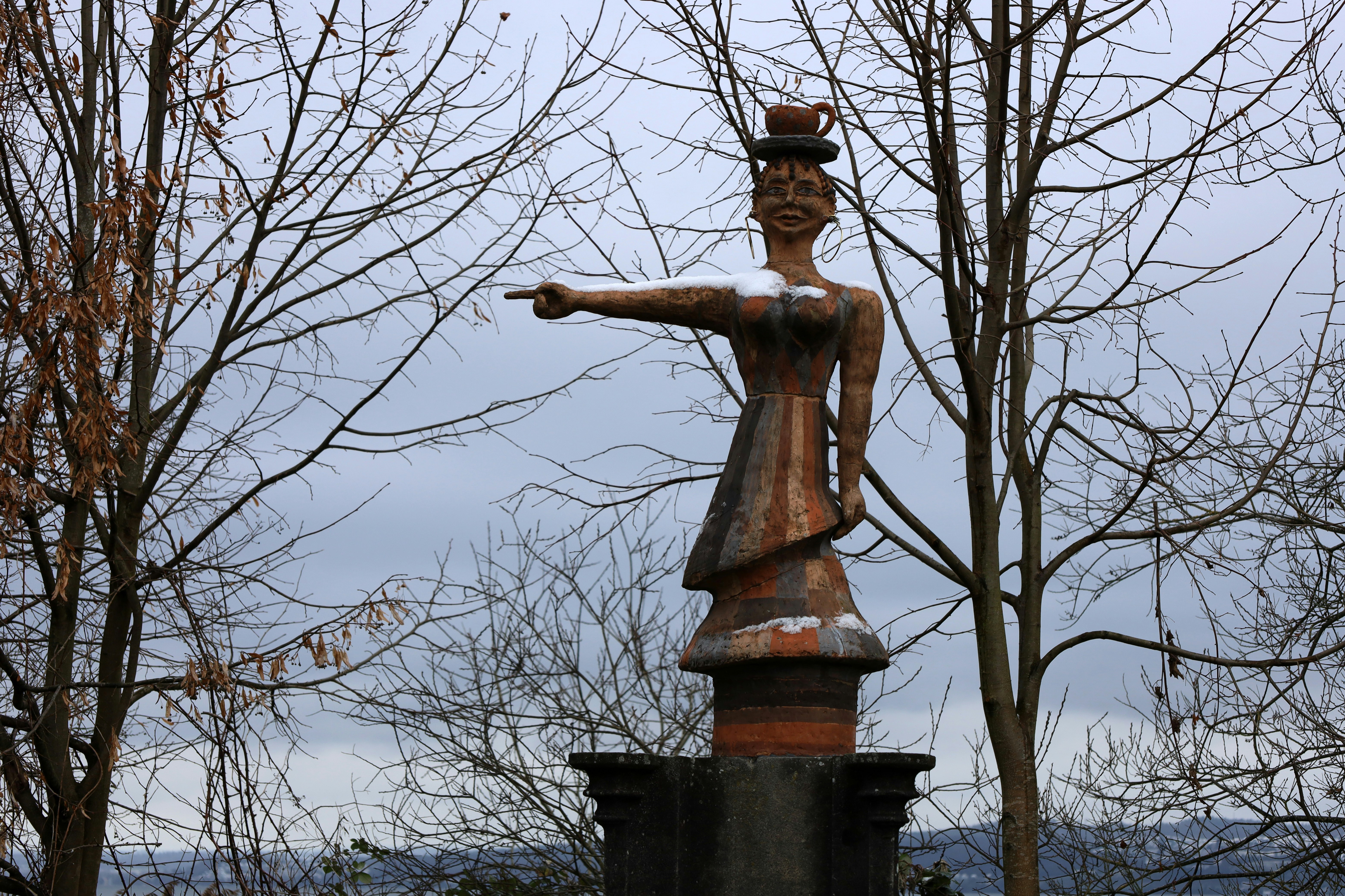 a statue of a woman with a hat on top of it