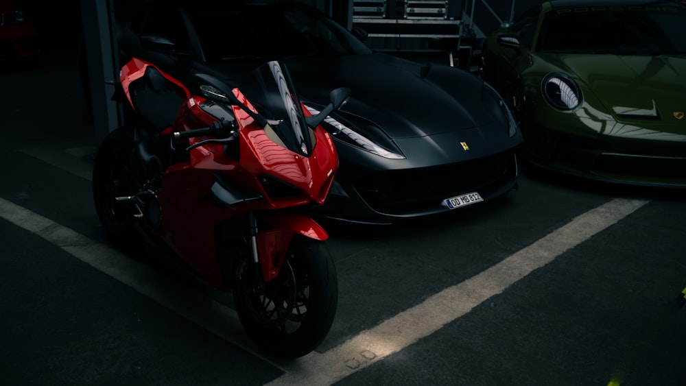 a red motorcycle parked next to a green car