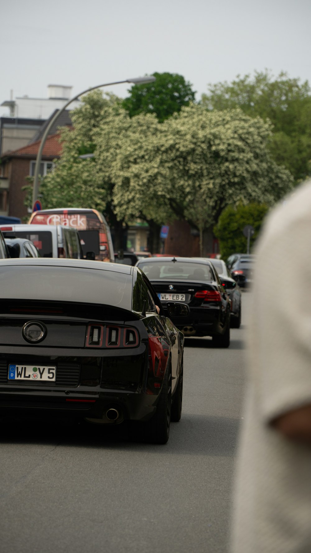 a black mustang is driving down a busy street