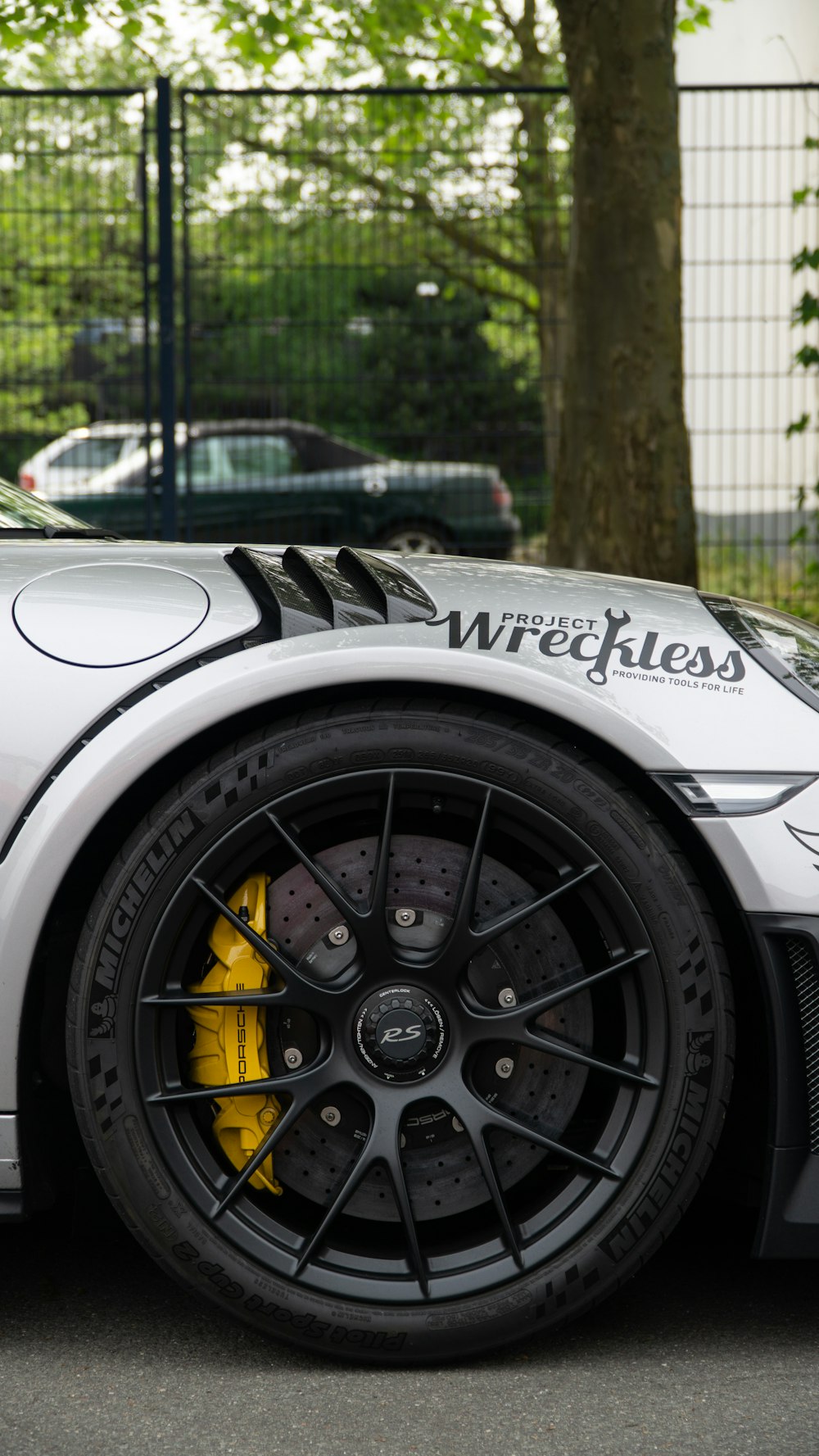 a white sports car parked in front of a fence