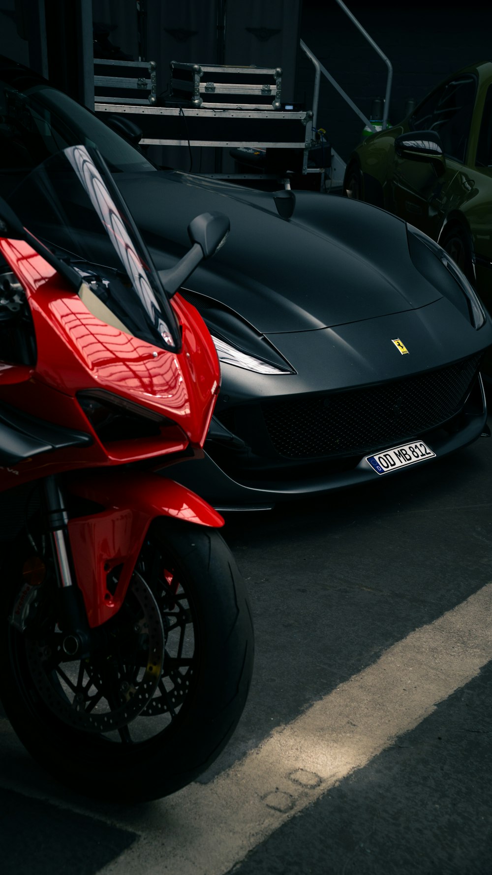 a red motorcycle parked next to a black car