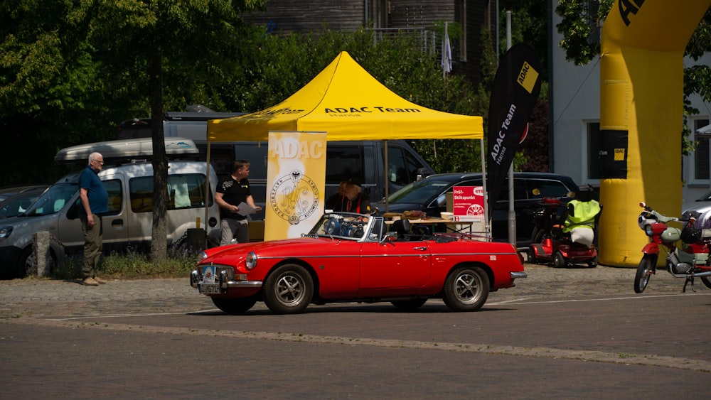 a red convertible car parked in front of a yellow tent