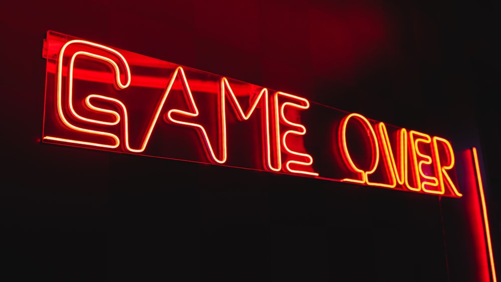 a neon sign that reads game over on a dark background