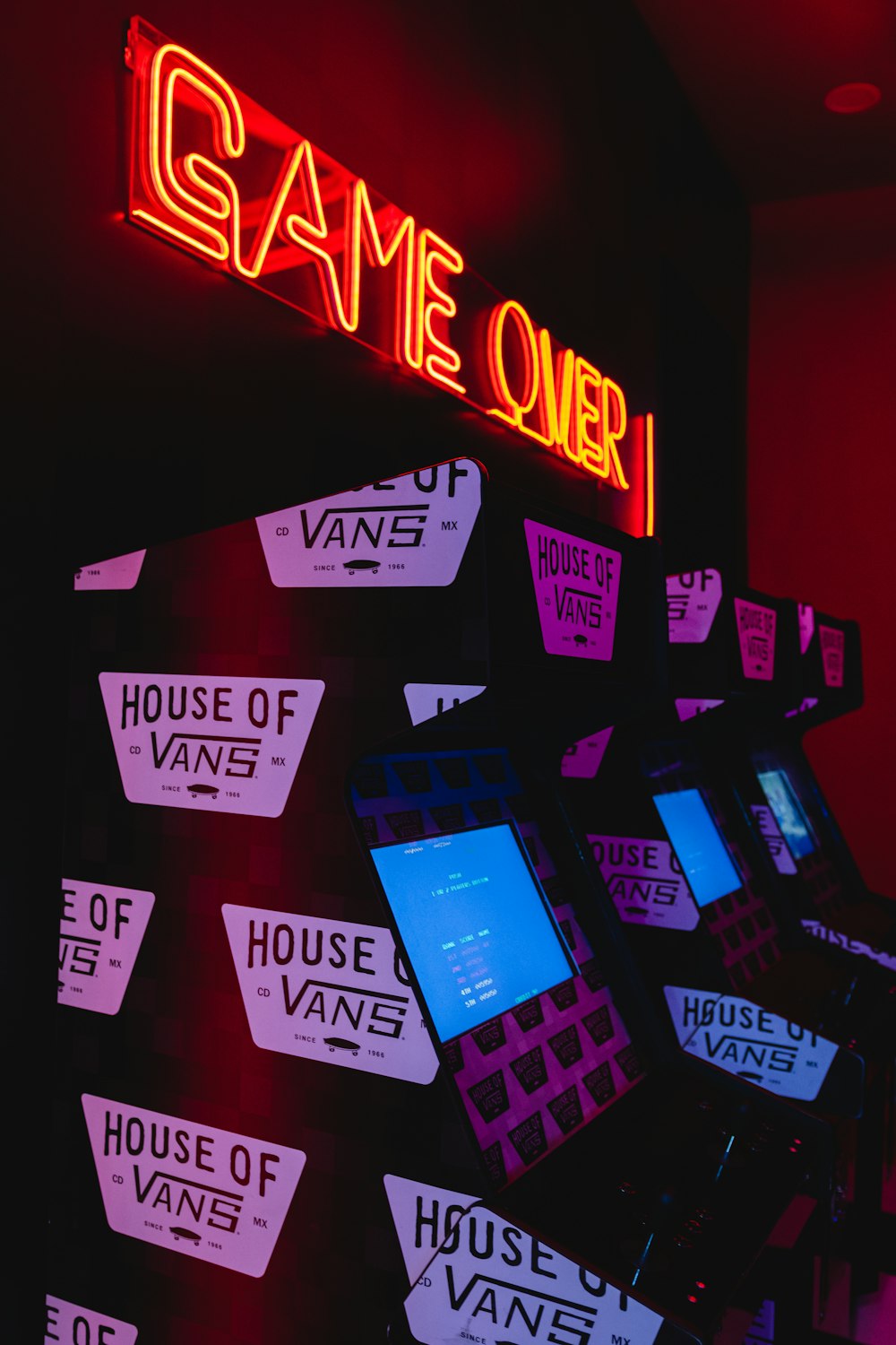 a game room with a neon sign and a bunch of electronic devices