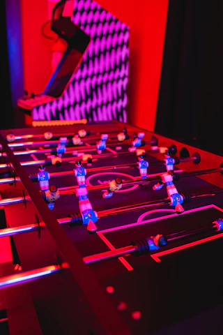 Friends enjoying a lively foosball game in the activity room at Cafe Qabil.