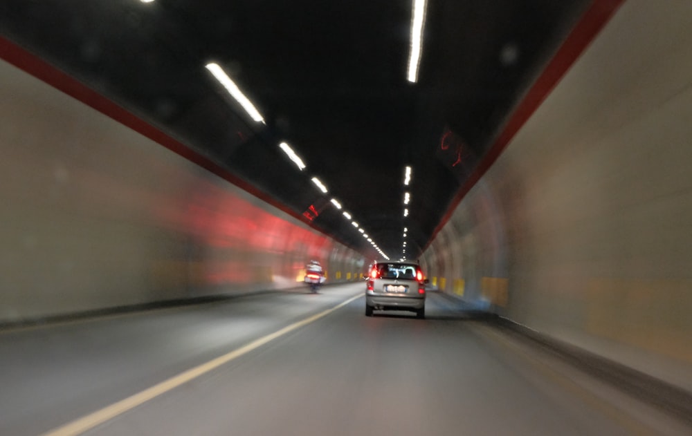 a car driving through a tunnel with lights on