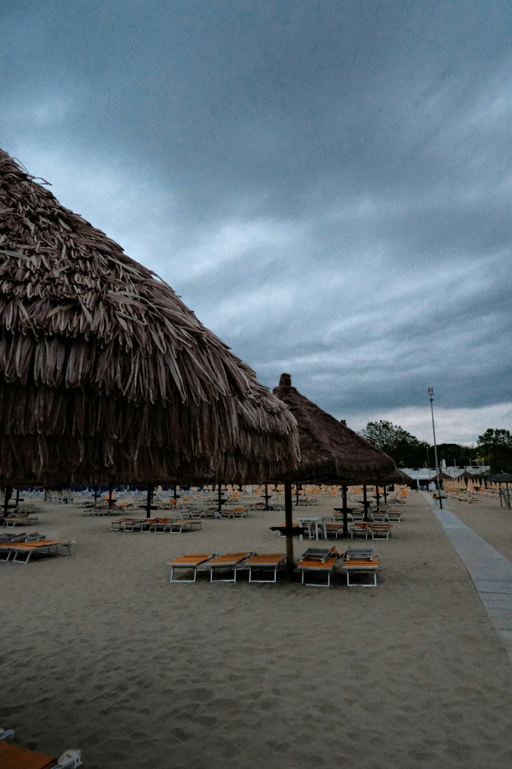 a row of beach chairs sitting under a thatched umbrella