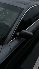 A sparkling clean car parked outdoors with water droplets glistening in the sunlight.