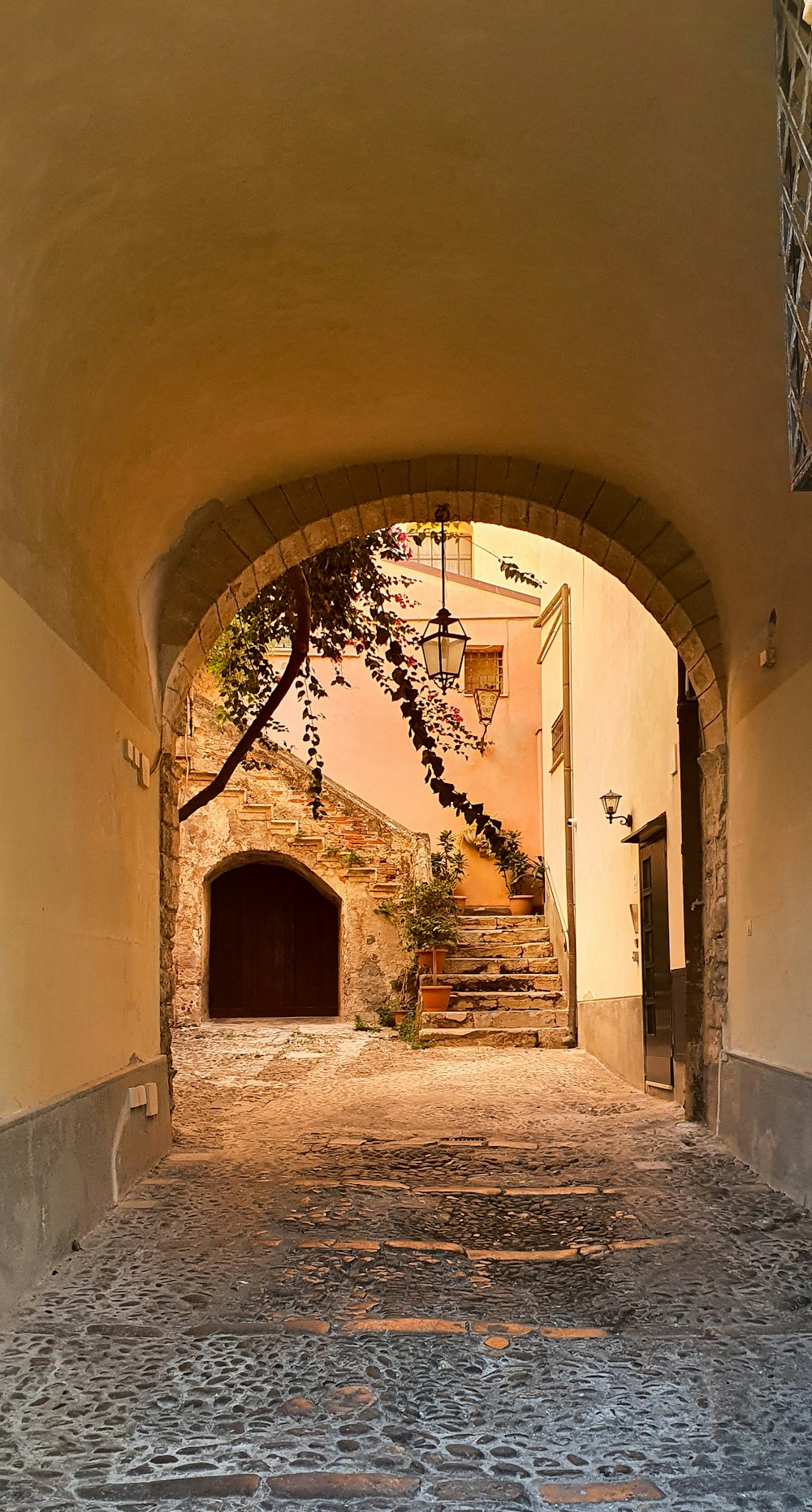 a cobblestone street with a stone arch leading into a tunnel