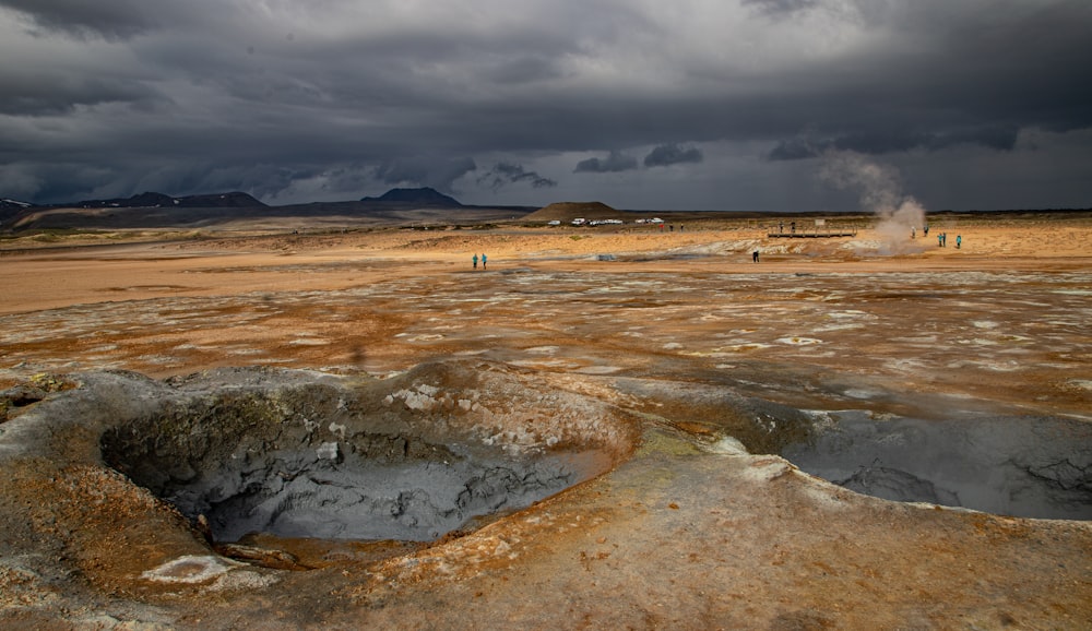a group of people standing in a barren area under a cloudy sky