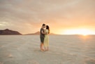 a couple embracing in the desert at sunset