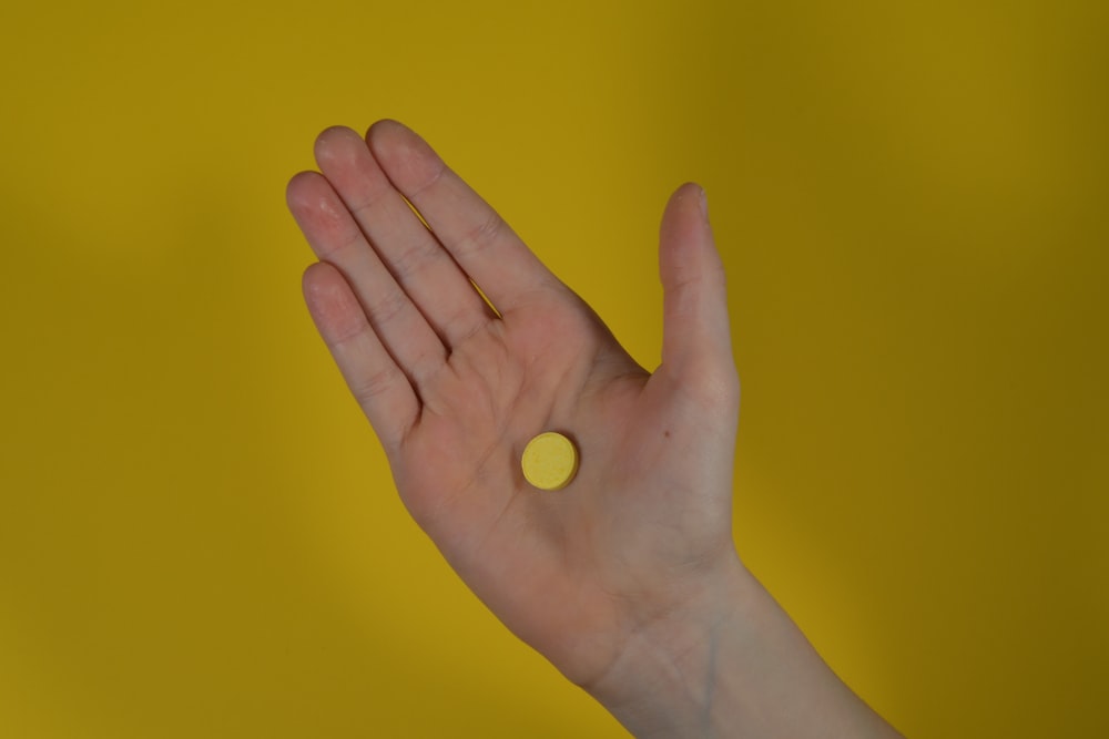 a person holding their hand out with a pill in it