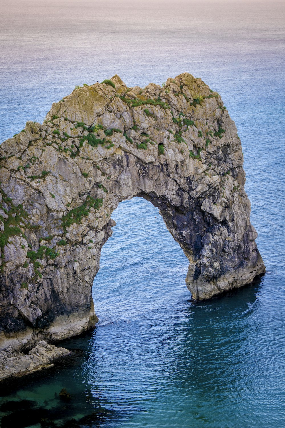 a large rock arch in the middle of a body of water