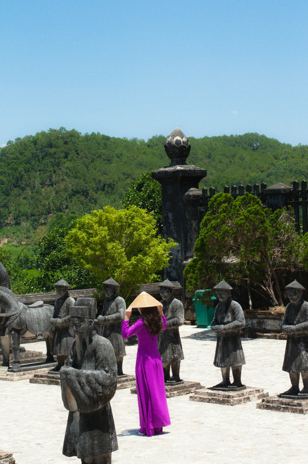 a woman in a purple dress standing in front of statues