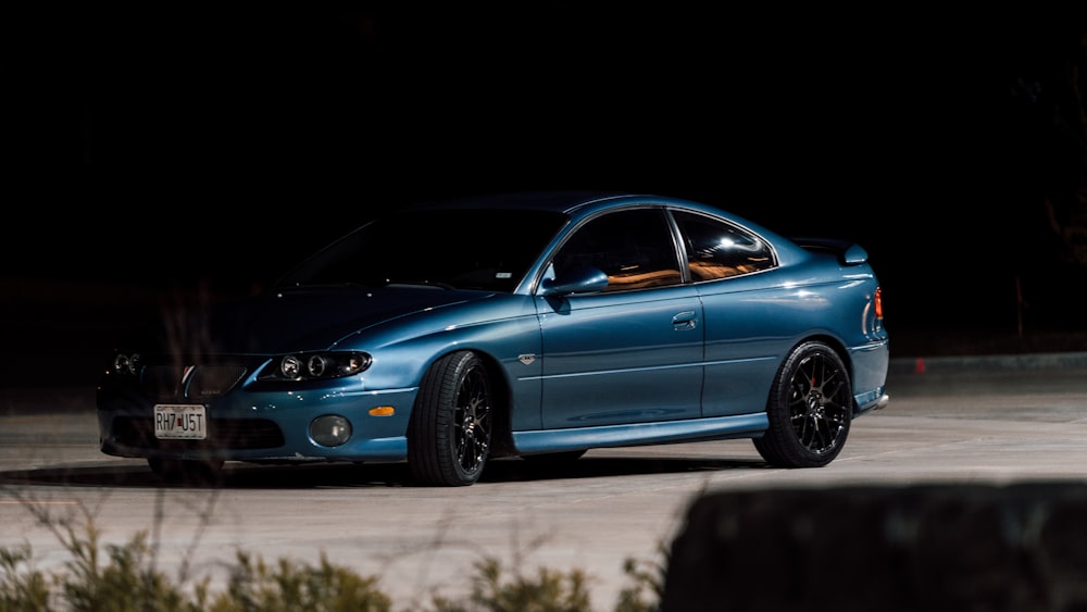 a blue car parked in a parking lot at night