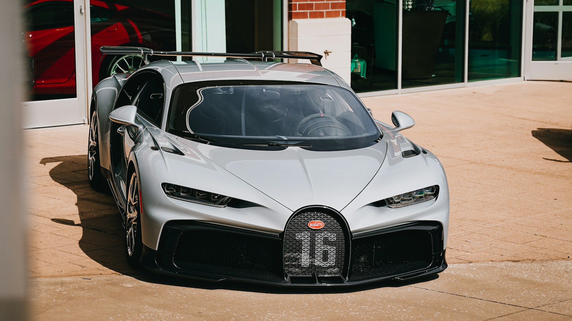 a silver bugatti is parked in front of a building