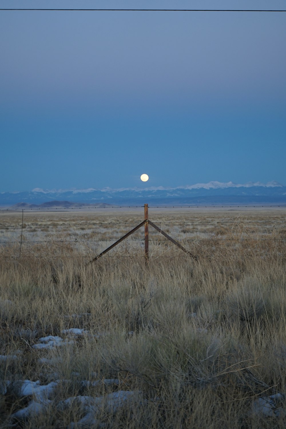 a field with a fence and a full moon in the sky