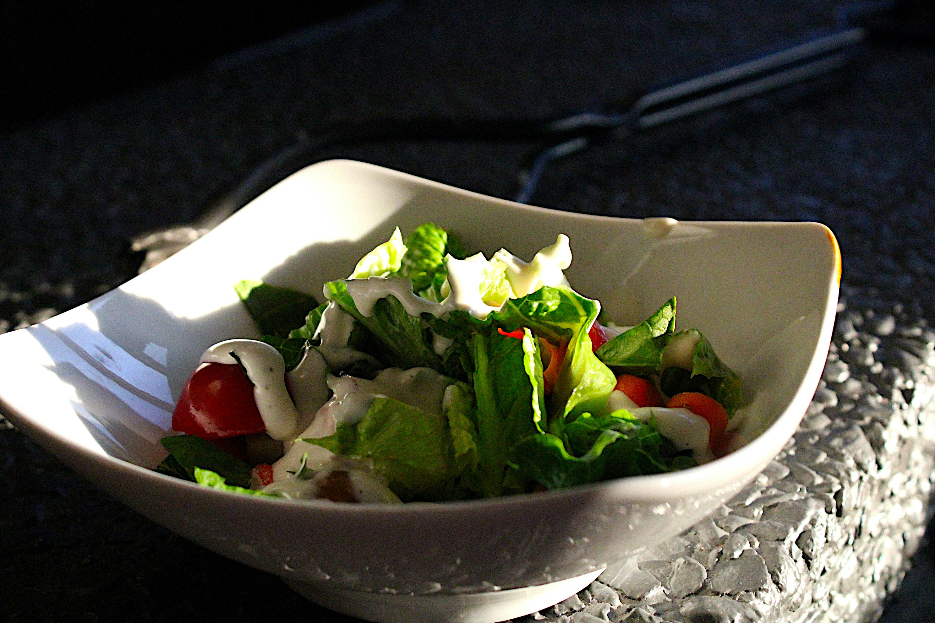 Fresh garden salad with colorful vegetables and house dressing in a bowl