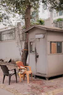 A sturdy guard hut painted in warm earth tones, positioned at the entrance of a residential property.