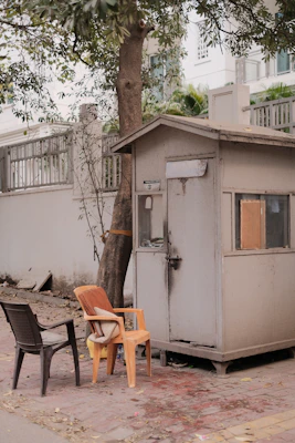 A sturdy guard hut painted in warm earth tones, positioned at the entrance of a residential property.