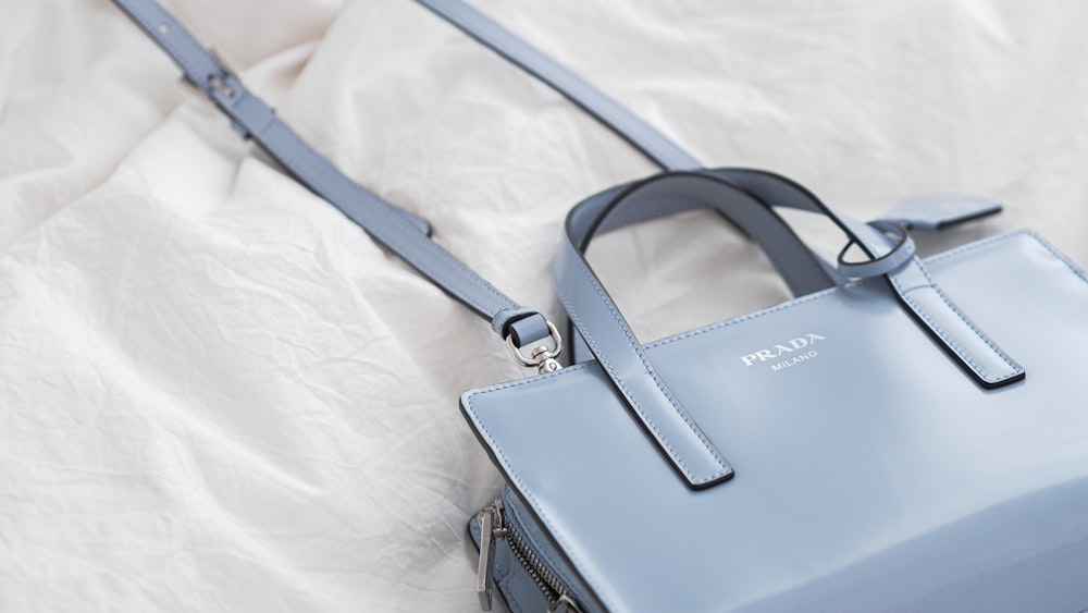 a blue purse sitting on top of a white sheet