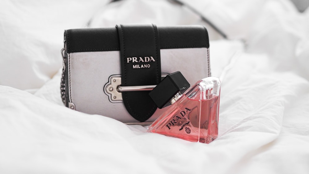 a purse and a bottle of perfume on a bed