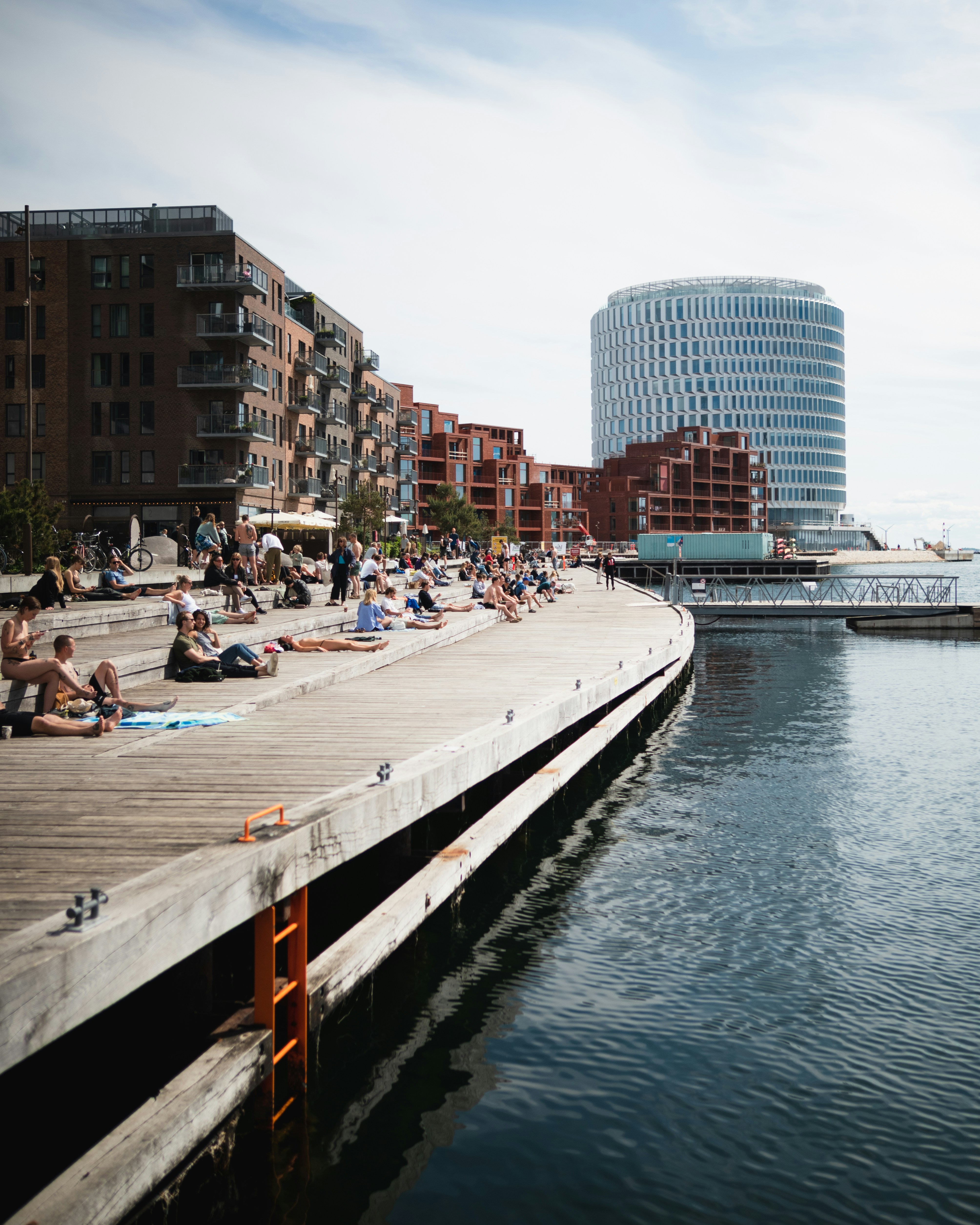 a group of people sitting on a pier next to a body of water