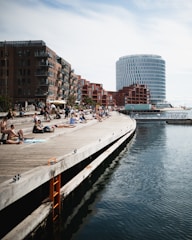 a group of people sitting on a pier next to a body of water