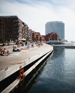 a group of people sitting on a pier next to a body of water