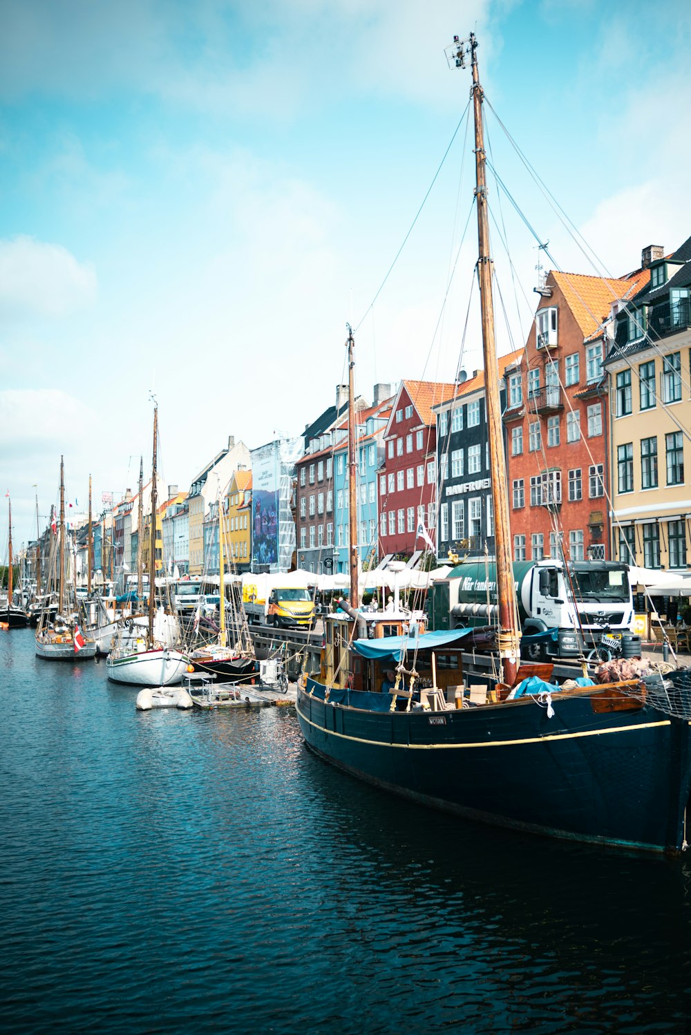 a row of boats docked in a harbor next to a row of buildings