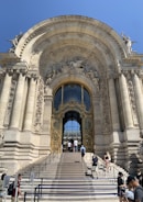 A grand entrance of a luxury home featuring tall pillars and intricate stonework.