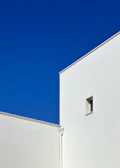 A minimalist urban scene with cool blue hues and sharp contrasts highlighting architectural lines.