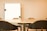 A meeting room with a large conference table surrounded by several black chairs. A whiteboard is mounted on the wall in the background, providing a professional setting.
