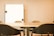 A meeting room with a large conference table surrounded by several black chairs. A whiteboard is mounted on the wall in the background, providing a professional setting.