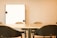 A meeting room with a large conference table surrounded by several black chairs. A whiteboard is mounted on the wall in the background, providing a professional setting.