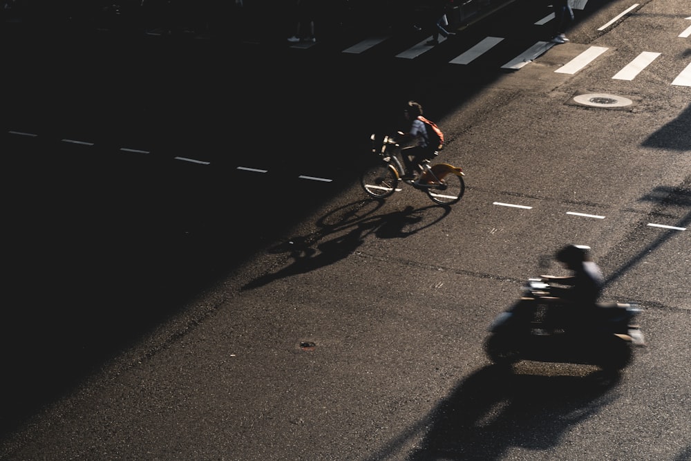 a man riding a bike down a street next to a motorcycle