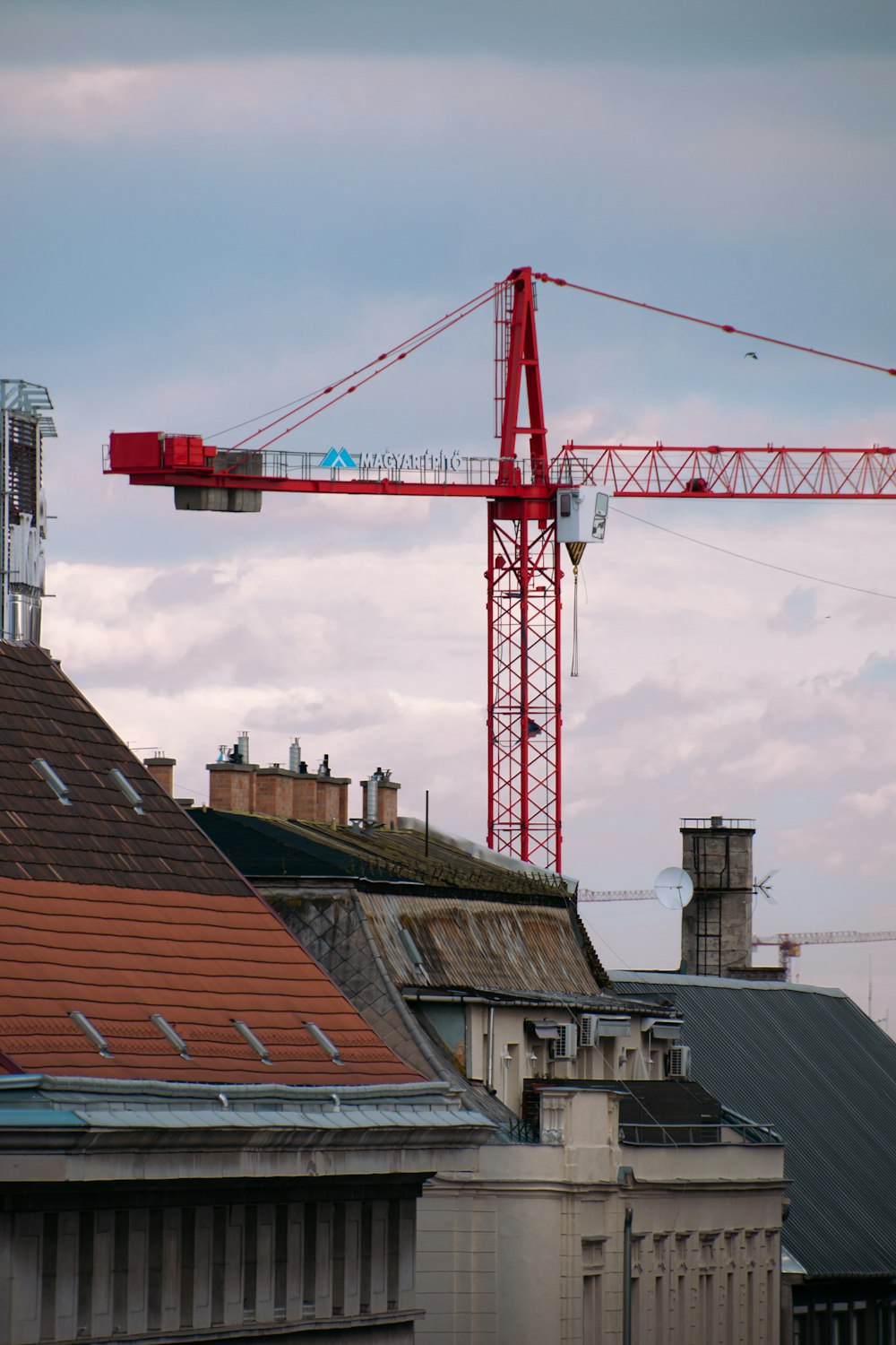 a red crane is on top of a building
