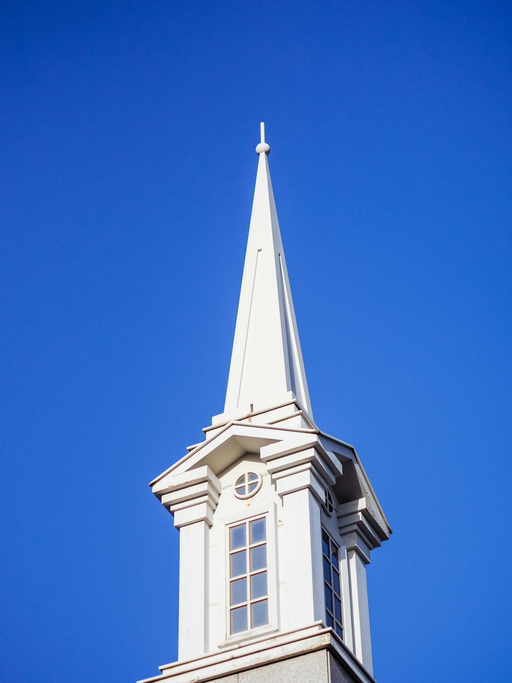 a white steeple with a clock on it against a blue sky