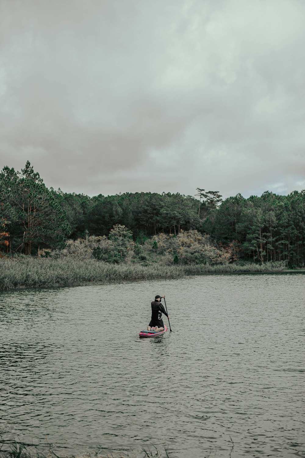 a man riding a paddle board on top of a lake