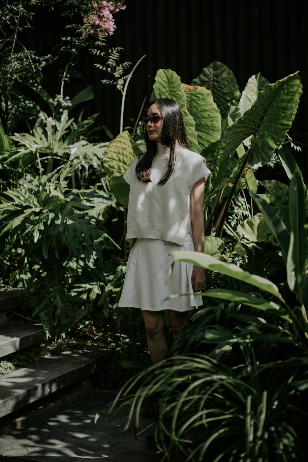 Une femme en robe blanche debout dans un jardin