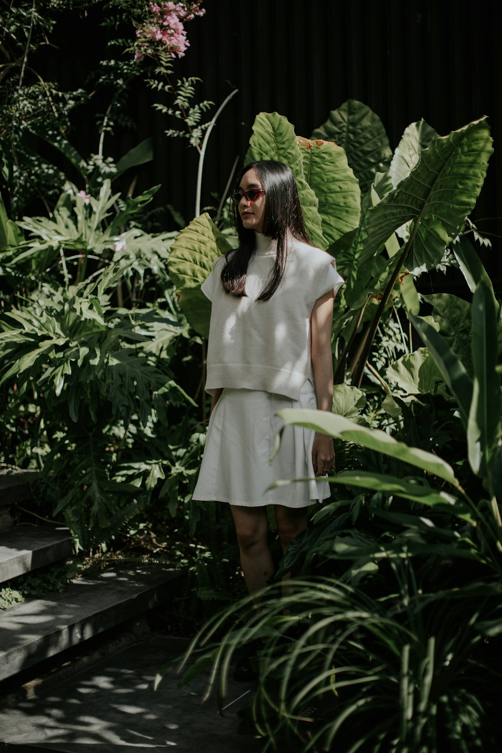 a woman in a white dress standing in a garden