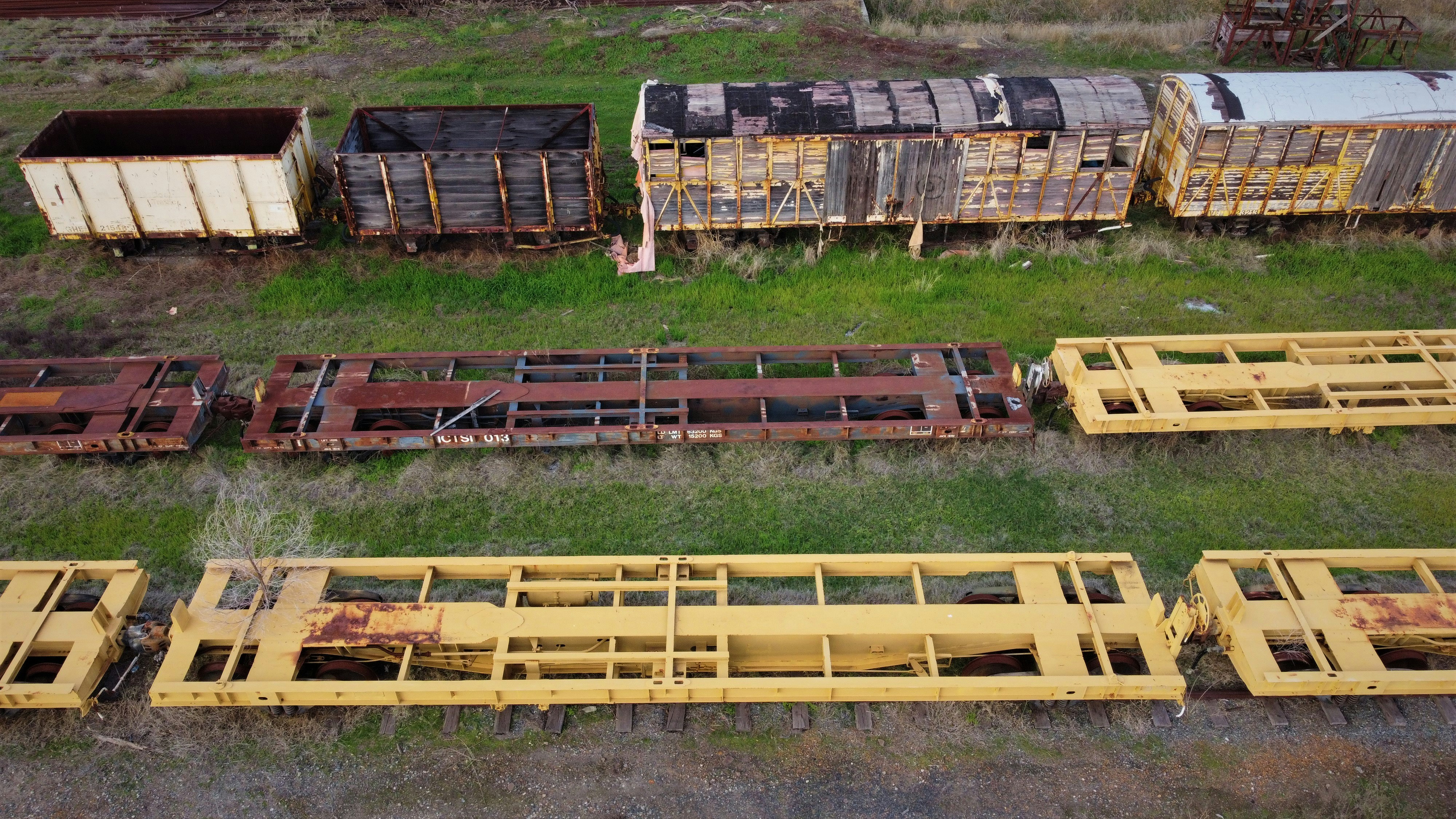 a group of train cars sitting on top of a grass covered field
