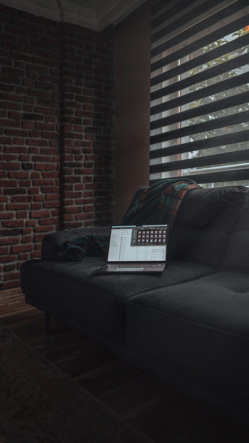 a laptop computer sitting on top of a black couch