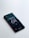 A smartphone placed on a light surface, displaying a lock screen with the time set to 10:04. The screen background features a teal and dark green abstract pattern.