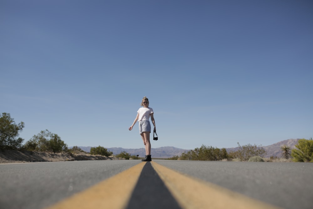 a woman walking down the middle of a road