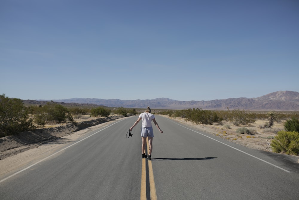 um homem andando de skate no meio de uma estrada
