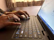 A close-up of hands typing on a laptop keyboard with a digital marketing course on screen.