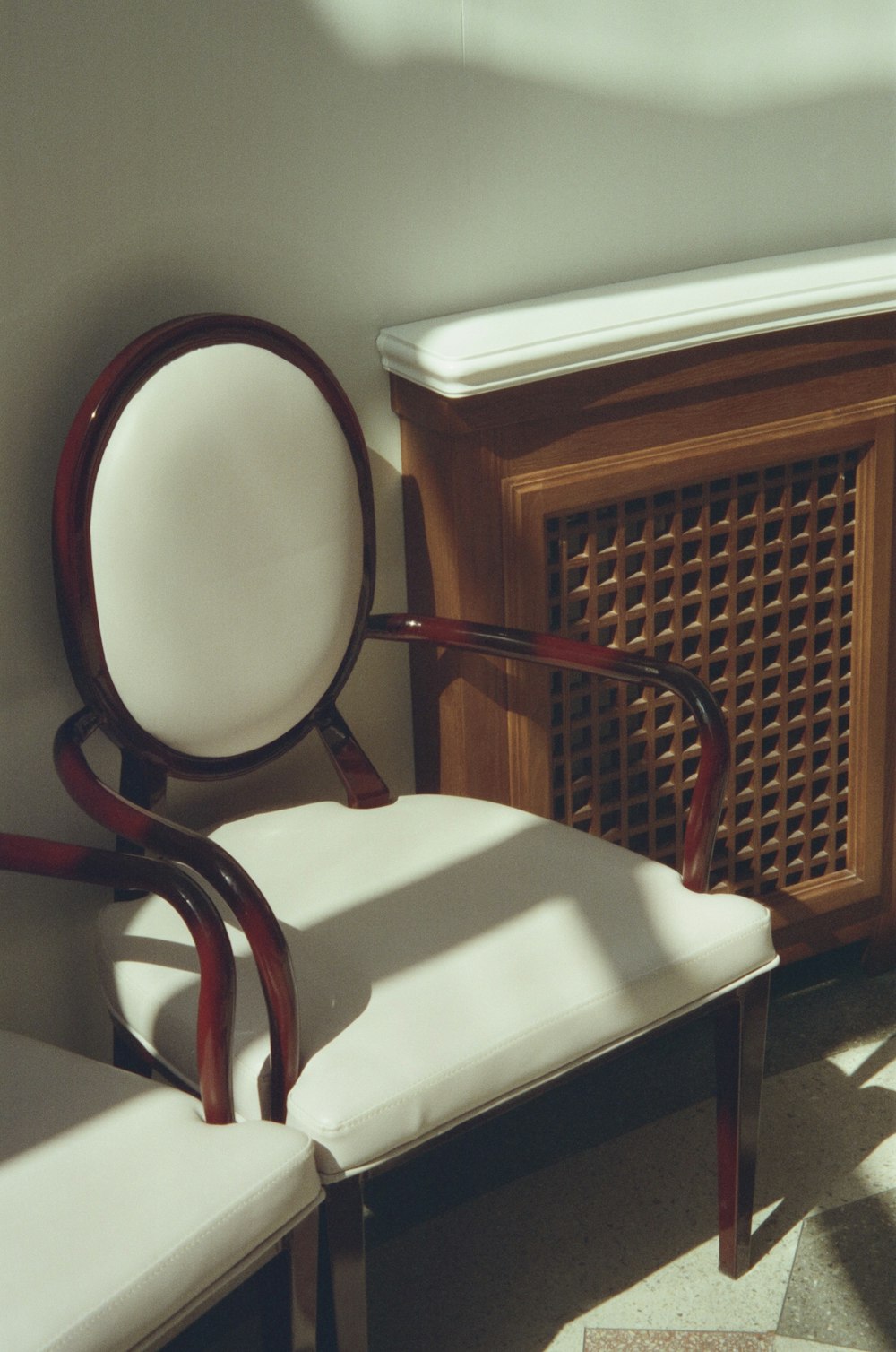 a white chair sitting next to a wooden cabinet